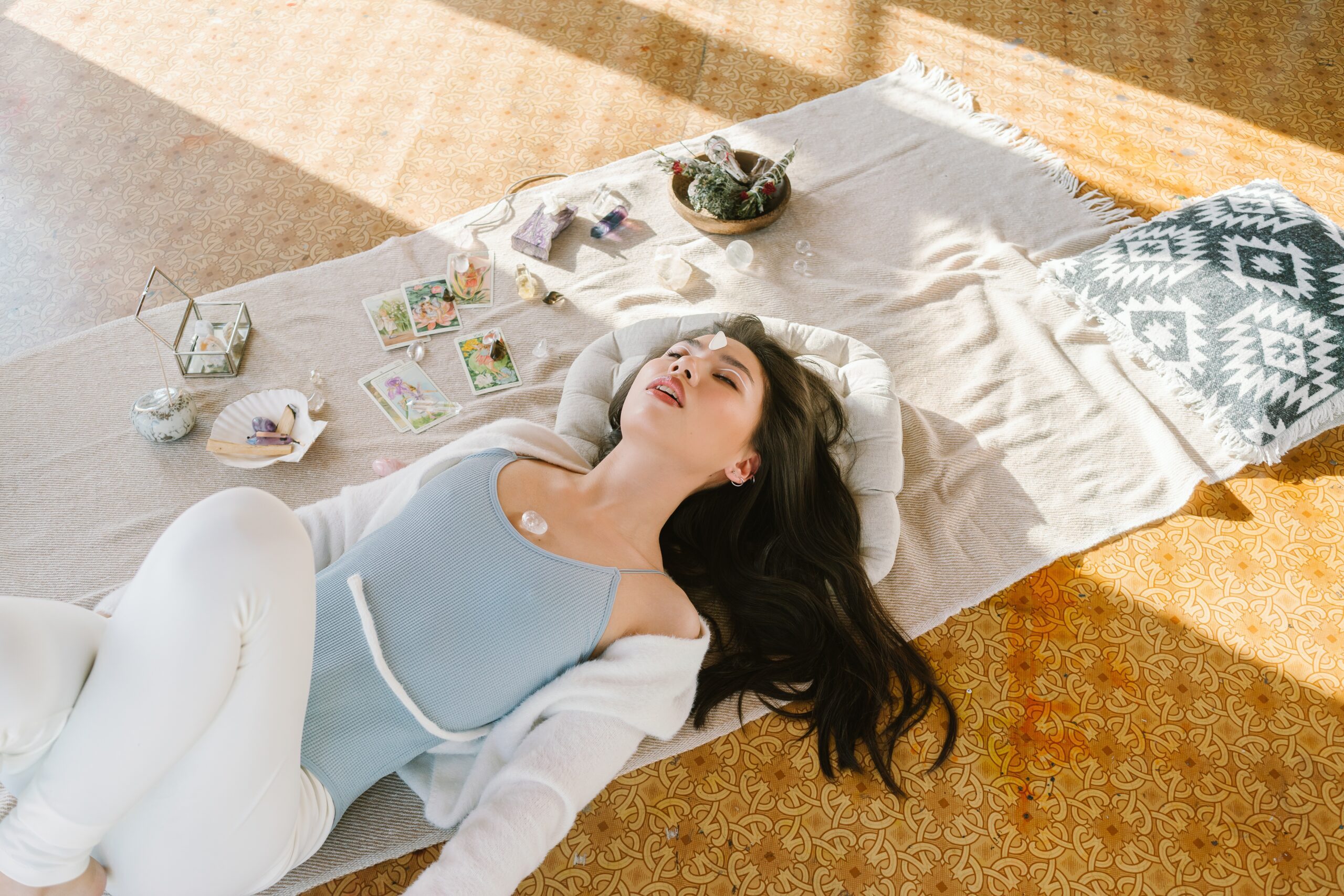 a model wearing a blue camisole and white shrug relaxing on a rug